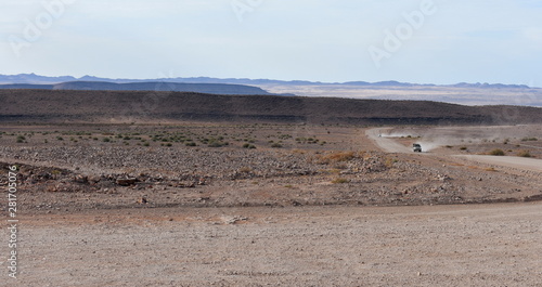 A car driving on a dirt road in the Namibian desert