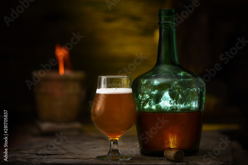 Botella con Cerveza Rubia y copa sobre mesa con fondo iluminado y jarrón con fuego