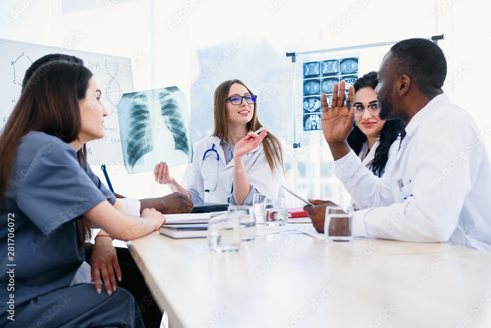 International team of young doctors discussing x rays result in the clinic. Showing patients results at modern progressive diagnostic centre. Medicine and healthcare concept. International team of young doctors discussing x rays result in the clinic. Showing patients results at modern progressive diagnostic centre. Medicine and healthcare concept.