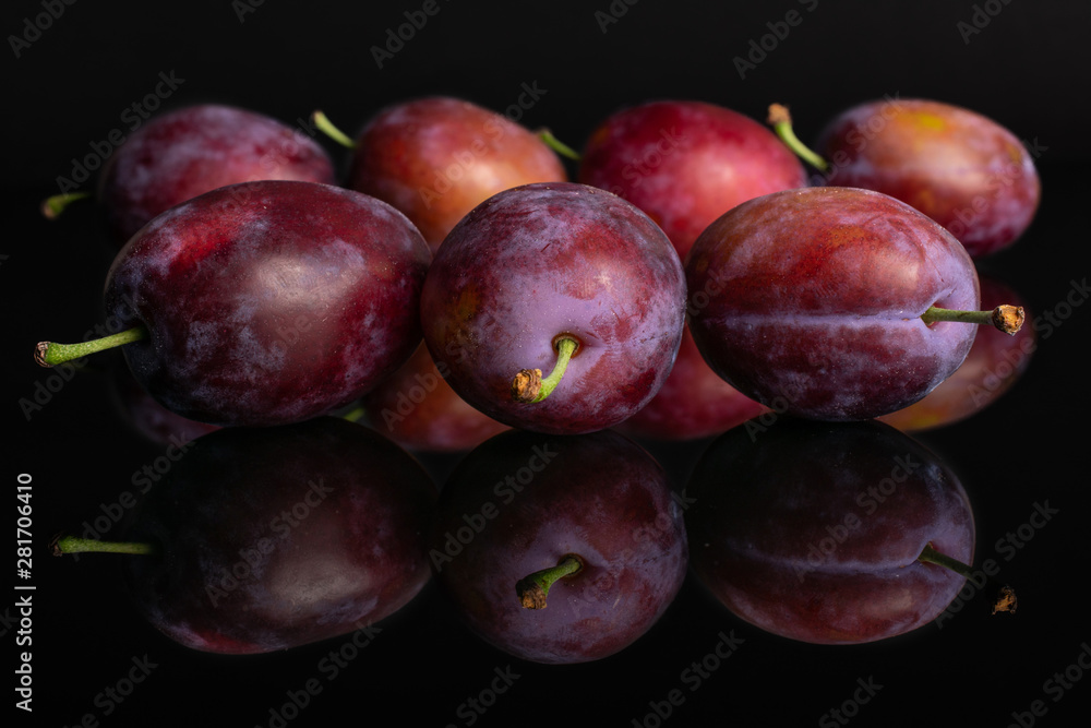 Lot of whole fresh blue plum isolated on black glass Lot of whole fresh blue plum isolated on black glass