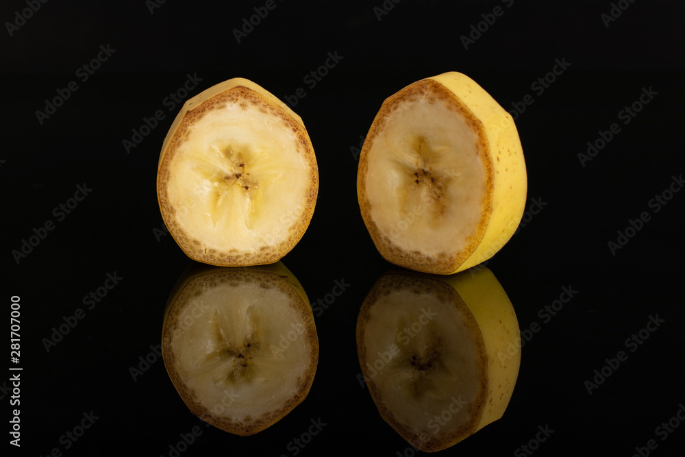 Group of two slices of ripe yellow banana isolated on black glass Group of two slices of ripe yellow banana isolated on black glass