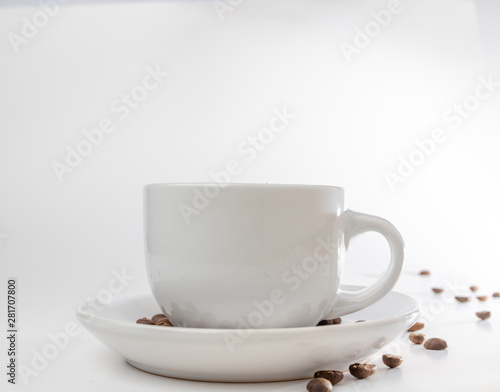 Coffee beans fall into a white porcelain cup and saucer  bouncing and jumping through the air conveying alert excitement  all isolated against a white background