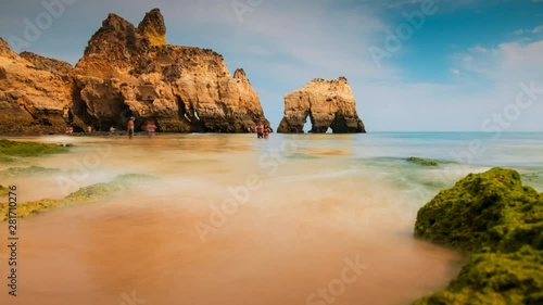 Amazing timelapse shot of pristine waters and beautiful rock formations in Tres Irmaos Beach in Alvor, The Algarve, Portugal photo