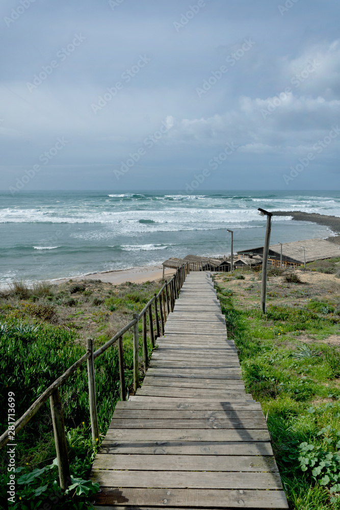 Obraz premium Beach landscape with wooden path with steps, waves, clouds