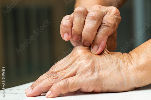 Senior Woman's right hand pinching her left hand, On white table background, Close up shot, Asian Body skin part, Healthcare concept photo