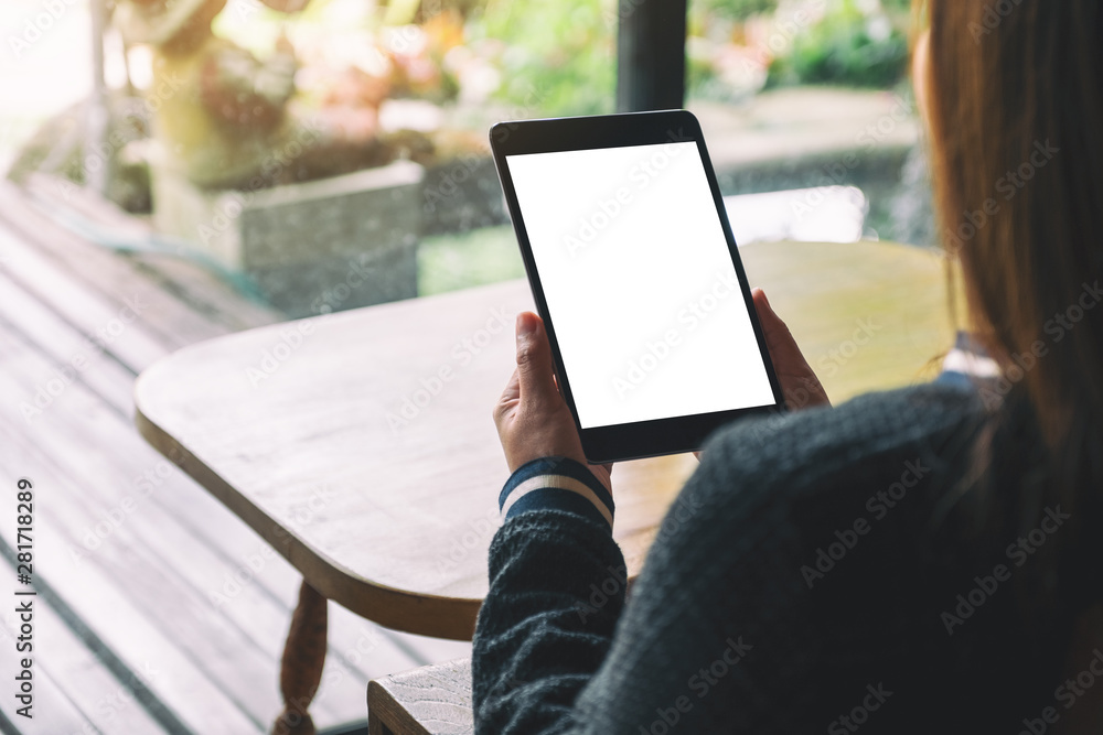 Mockup image of a woman sitting and holding black tablet with blank white desktop screen Mockup image of a woman sitting and holding black tablet with blank white desktop screen