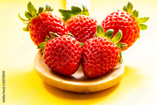 Fototapeta Naklejka Na Ścianę i Meble -  strawberries in a wooden spoon and yellow background