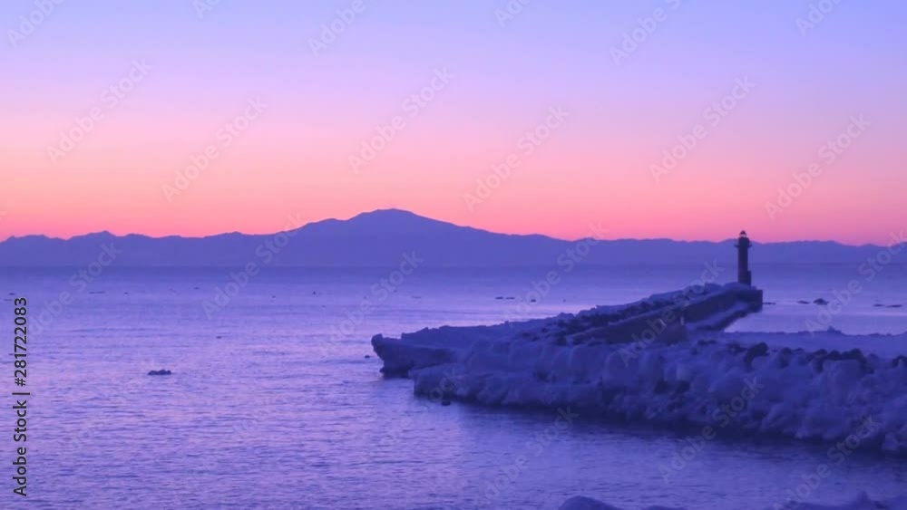 Lighthouse on snow-covered coast with mountains in background Lighthouse on snow-covered coast with mountains in background
