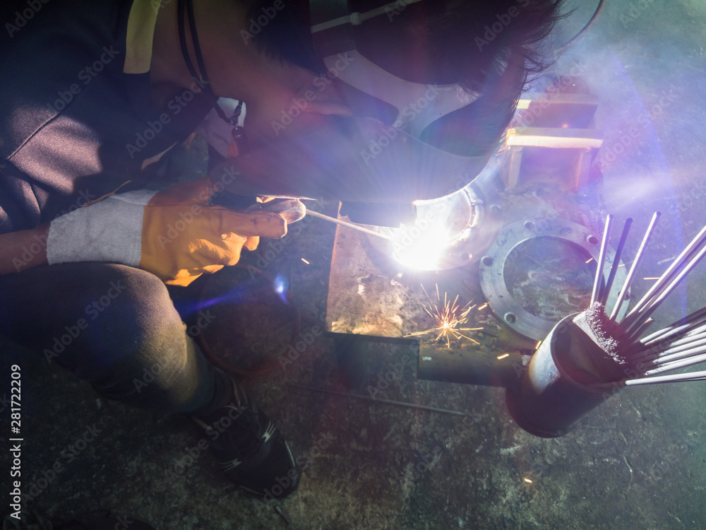 Close up worker welding steel with smoke and colourful of lights in industrial work shop.