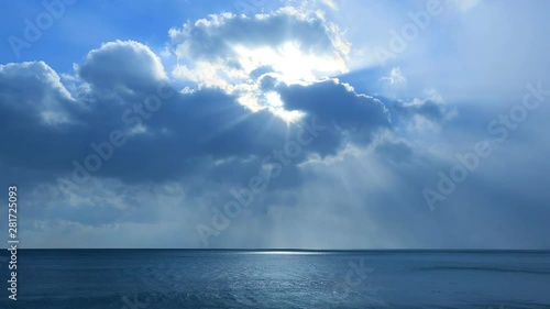 Sunlight piercing clouds over blue sea photo
