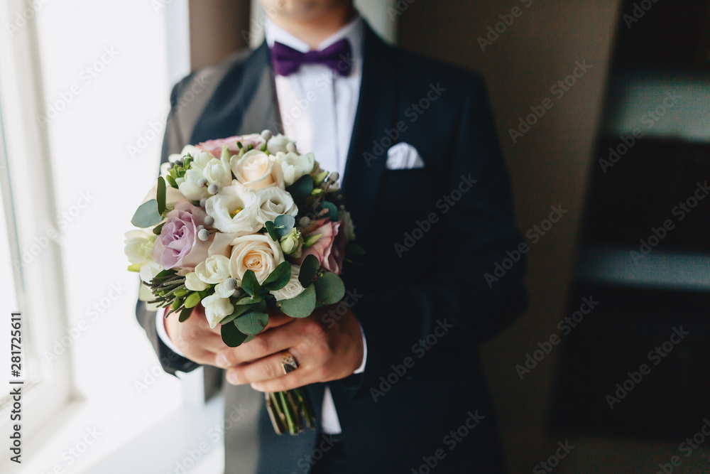 the groom holds a wedding bouquet in his hands the groom holds a wedding bouquet in his hands