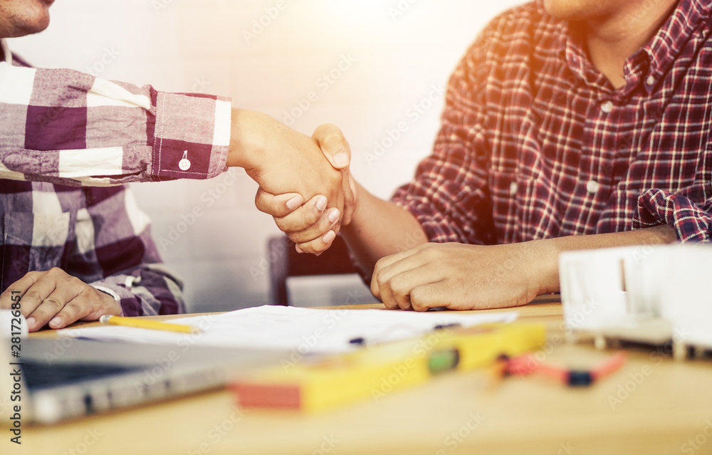 Success collaboration concept. architect engineer shaking hands in the workplace, with a new architectural house model.