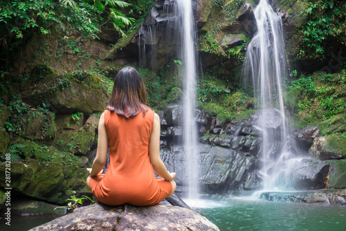 Female doing yoga outdoor exercise for Health is relaxation at beautiful waterfall.