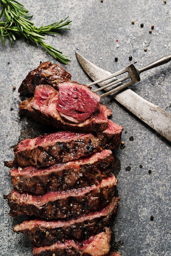 Prime Rib Steak on natural stone slab with old knife and fork photo