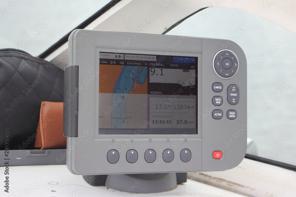 Close-up grey modern chartplotter device ob Motor boat dashboard, inscription on screen in Russian: local time, depth, map, trip, find, view