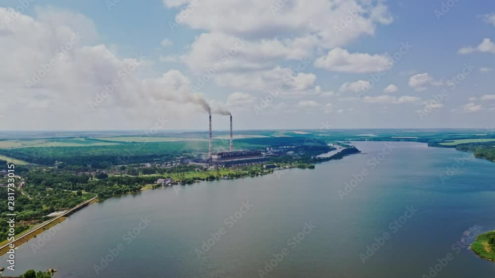 Beautiful scenery of the river background and plant with pipes. Natural landscape of blue water, green fields and factory nearby. Aerial view. Motion up. Beautiful scenery of the river background and plant with pipes. Natural landscape of blue water, green fields and factory nearby. Aerial view. Motion up.