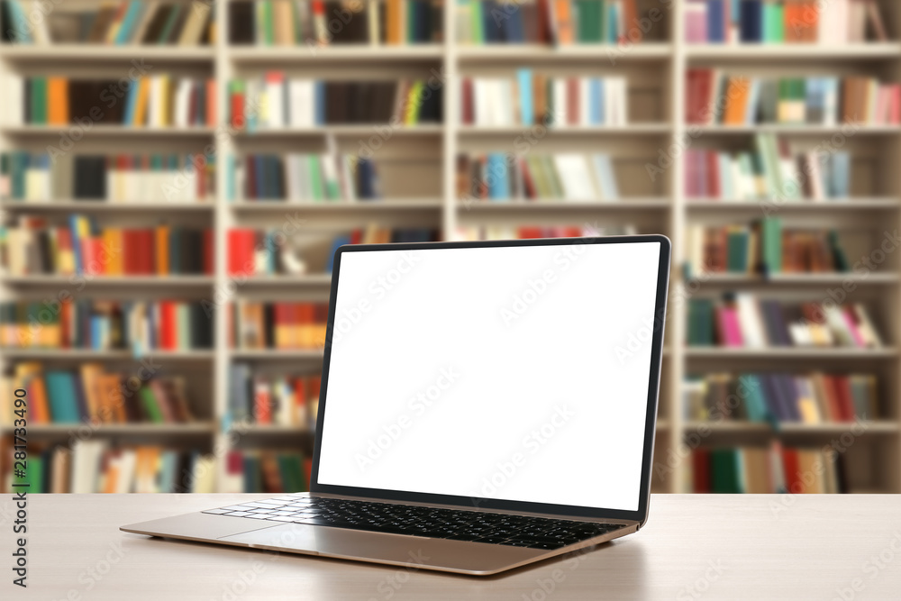 Modern laptop with empty screen on table in library. Space for design Modern laptop with empty screen on table in library. Space for design