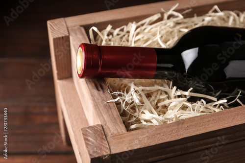 Open wooden crate with bottle of wine, closeup