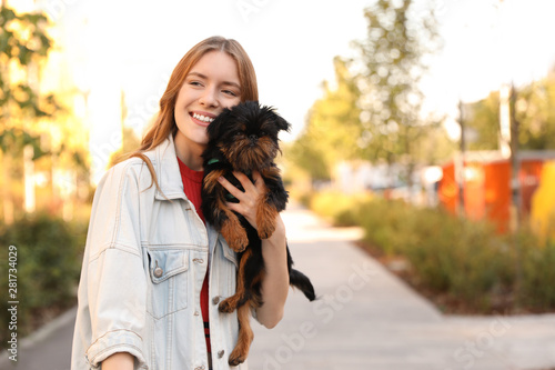 Young woman with adorable Brussels Griffon dog in park. Space for text