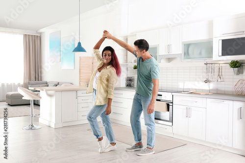 Beautiful couple dancing in kitchen at home