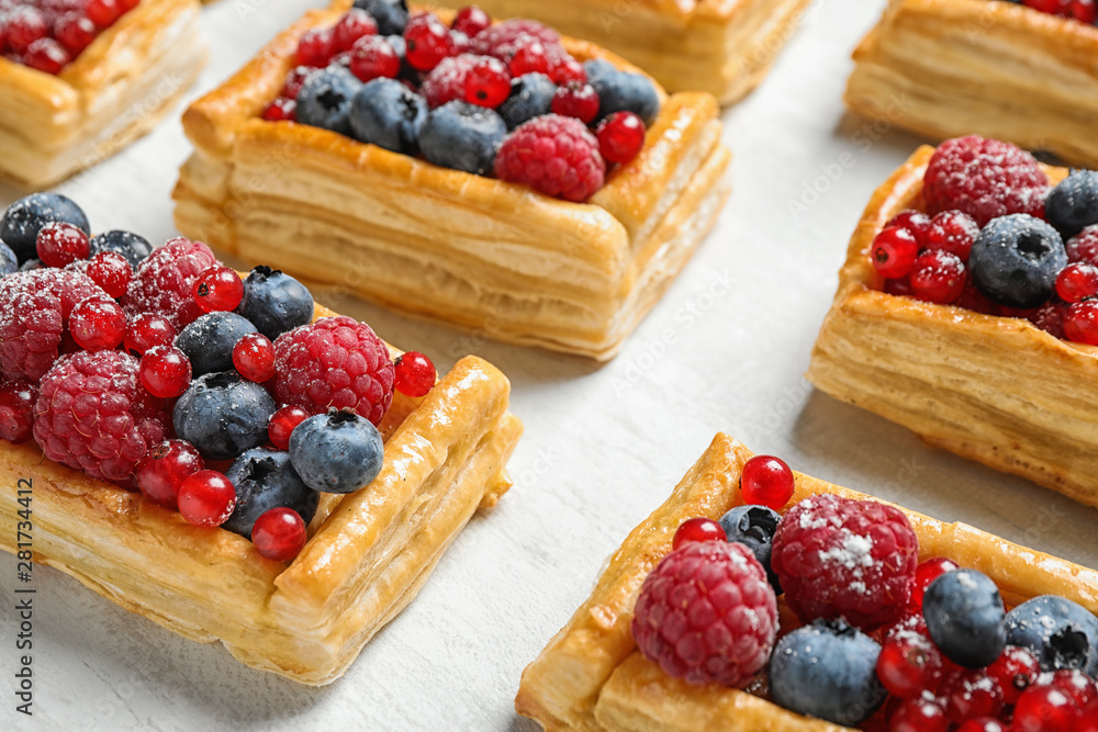 Fresh delicious puff pastry with sweet berries on light table, closeup Fresh delicious puff pastry with sweet berries on light table, closeup