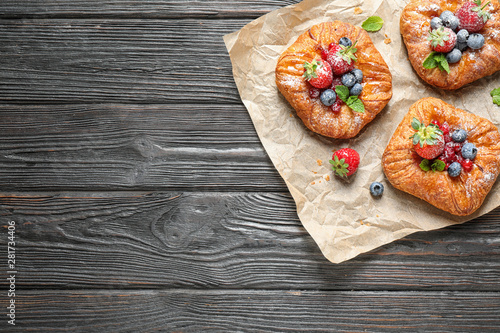 Fresh delicious puff pastry with sweet berries on dark wooden background, top view. Space for text © New Africa