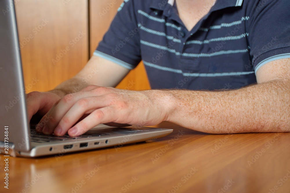 Closeup of the man's hand with freckles. Midsection of the young man typing on the laptop Closeup of the man's hand with freckles. Midsection of the young man typing on the laptop