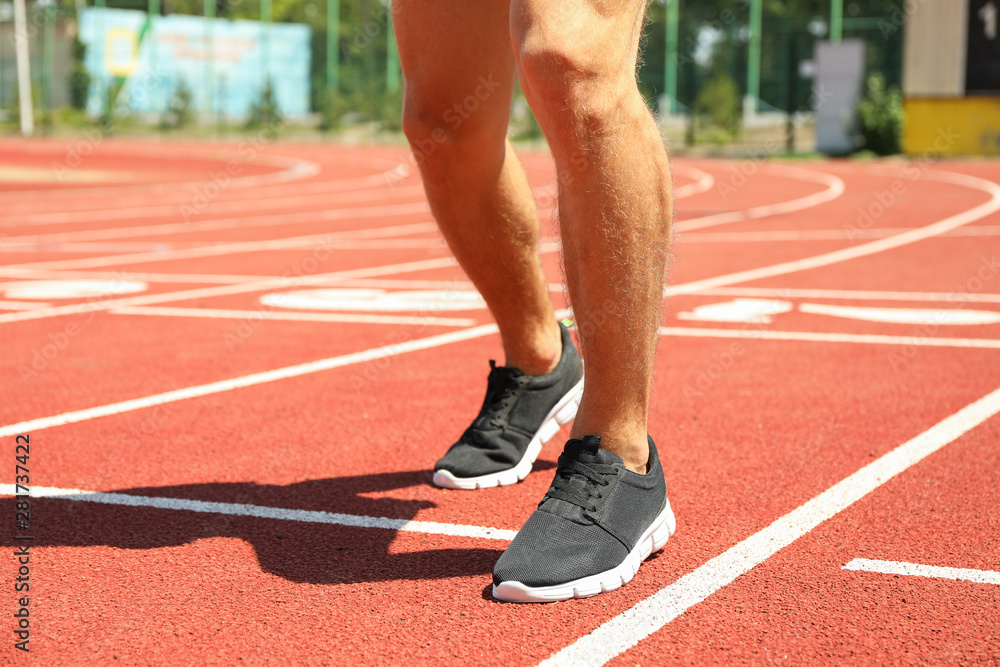 Man in sneakers on red athletic running track, close up