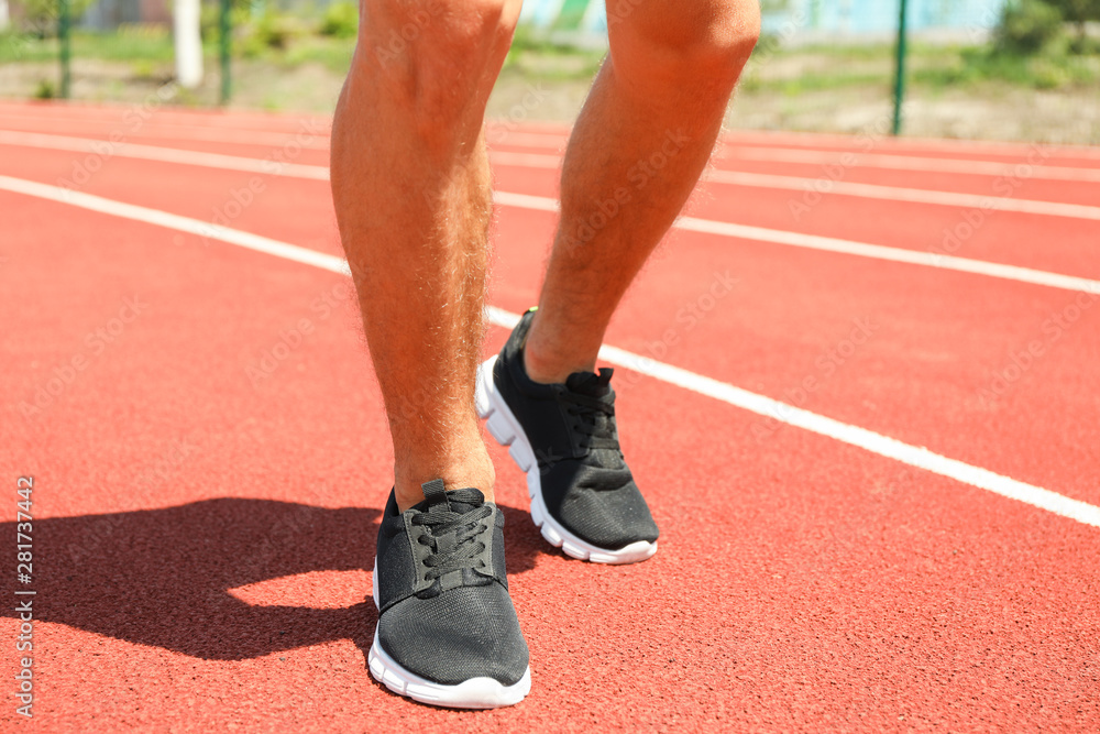 Man in sneakers on red athletic running track, close up