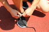 Man tying shoelaces on red athletic running track, close up