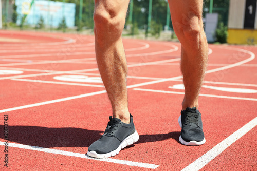 Man in sneakers on red athletic running track, close up