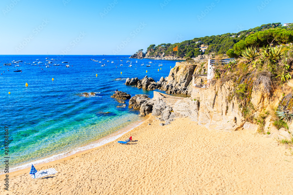 Sun chairs and umbrella on picturesque beach in Calella de Palafrugell fishing village, Costa Brava, Catalonia, Spain