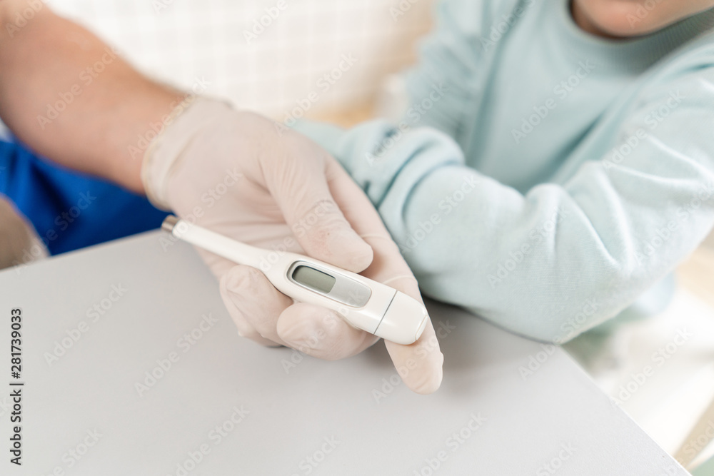 Male arm hold electronic thermometer showing high temperature. Pediatrician in the hospital Male arm hold electronic thermometer showing high temperature. Pediatrician in the hospital