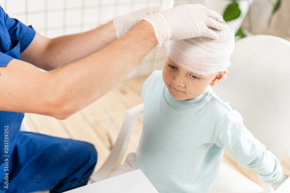 Obraz premium Sports injury. Doctor makes bandage on head patient, in the hospital.