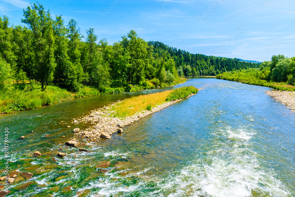 Dunajec river with green hills on shore on sunny summer day near Nowy Targ, Tatra Mountains, Poland Dunajec river with green hills on shore on sunny summer day near Nowy Targ, Tatra Mountains, Poland