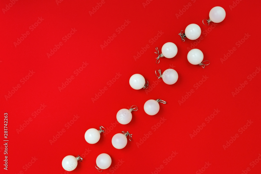 Minimal New Year greeting card with white glass balls on red colored background. Christmas flat lay border with copy space. Top view. Minimal New Year greeting card with white glass balls on red colored background. Christmas flat lay border with copy space. Top view.