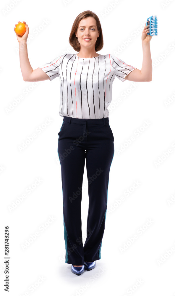 Young businesswoman with cleaning brush and fruit on white background. Concept of balance Young businesswoman with cleaning brush and fruit on white background. Concept of balance