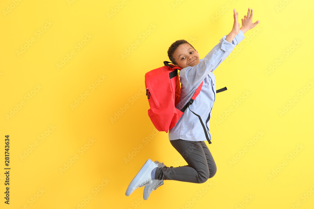 Jumping African-American schoolboy on color background - obrazy, fototapety, plakaty 