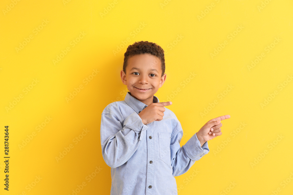 Cute African-American boy pointing at something on color background Cute African-American boy pointing at something on color background