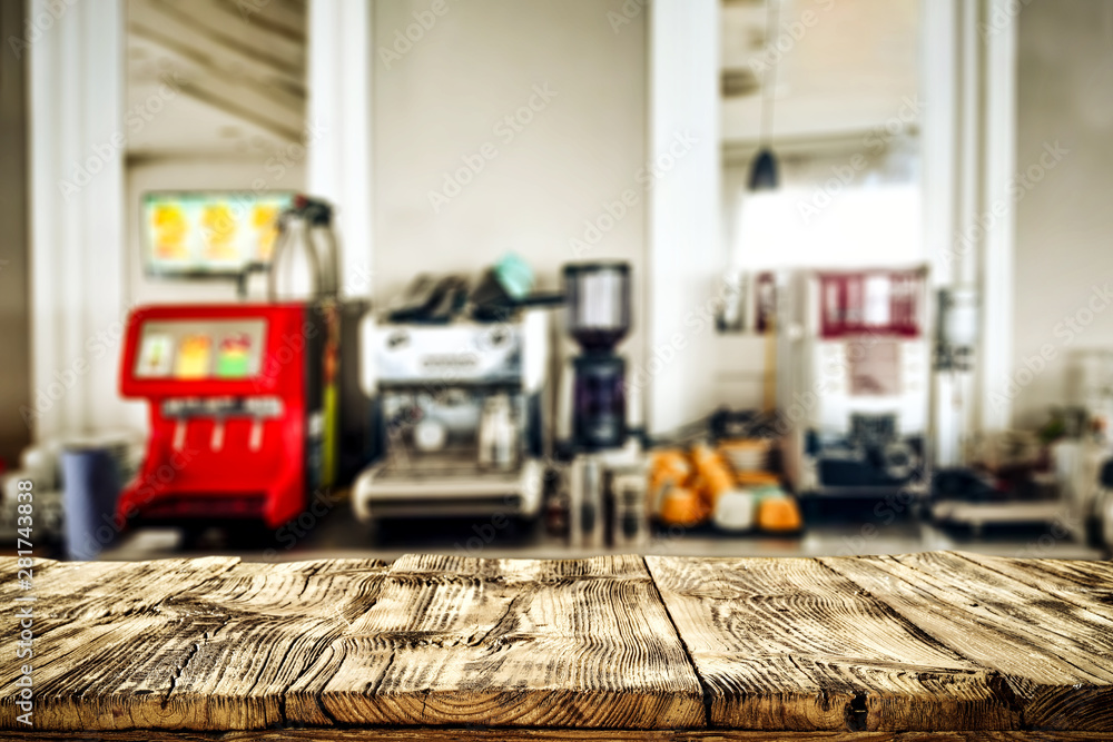 Wooden table top with blurred juice squeezer and coffee express  view.
