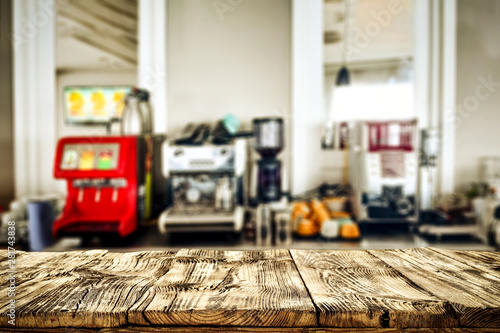 Wooden table top with blurred juice squeezer and coffee express view.