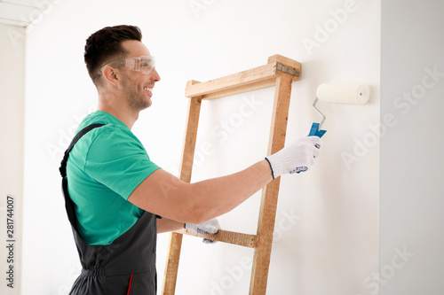 Male decorator painting light wall
