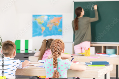 Cute little pupils during lesson in classroom