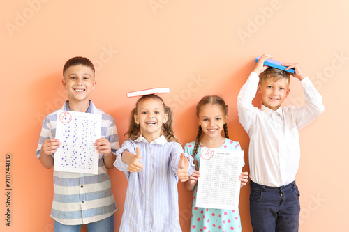 Happy children with answer sheets for school test on color background