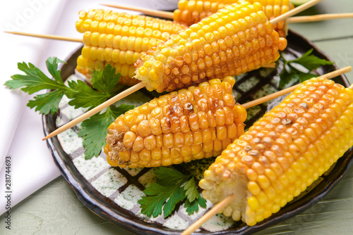 Plate with tasty grilled corn cobs on table