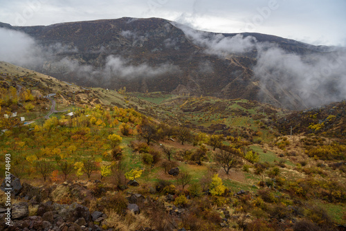 Mountains shrouded in mist in the season of golden autumn on a cloudy day, view of the gorge from the top of the mountain.