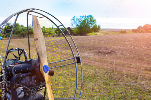 Closeup of a propeller with a motor-paraglider motor against the background of a field.