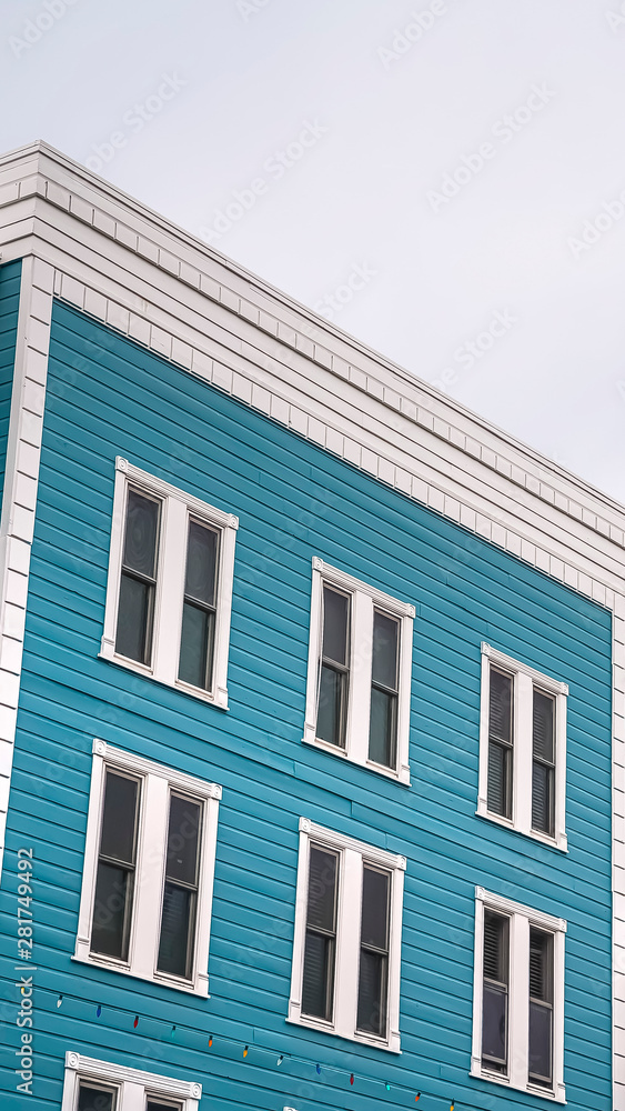 Vertical Residential building with blue exterior wall and vertical sliding windows