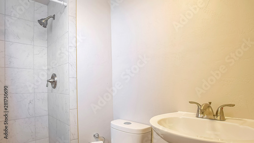 Panorama Stand alone sink toilet and shower inside a small bathrrom with white wall