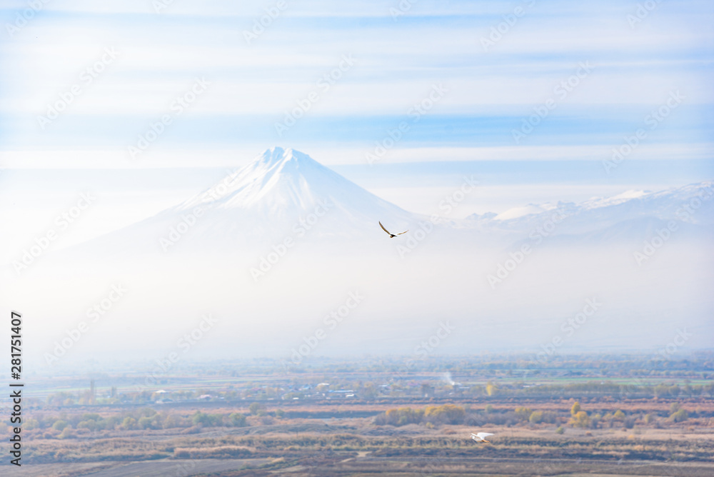 Mount Ararat is located on the Turkish territory with a view from the territory of Armenia from a high mountain near the Khor Virap monastery on a bright sunny day, with a hazy mist on the sky in the 